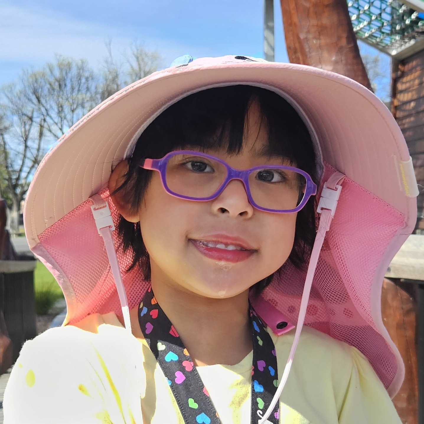 Maria smiling in her pink sun hat and purple glasses